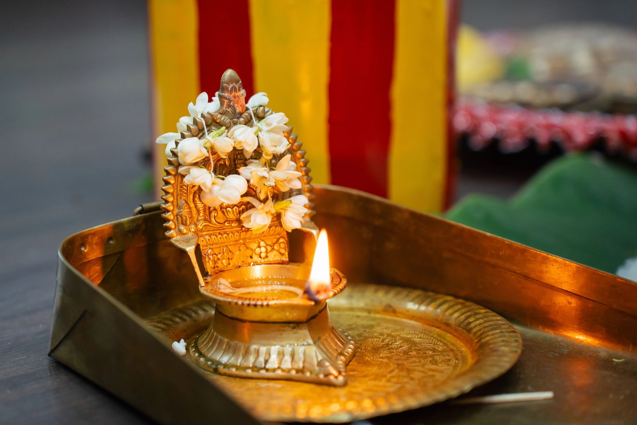 Brass oil lamp decorated with jasmine flowers during ritual ceremony